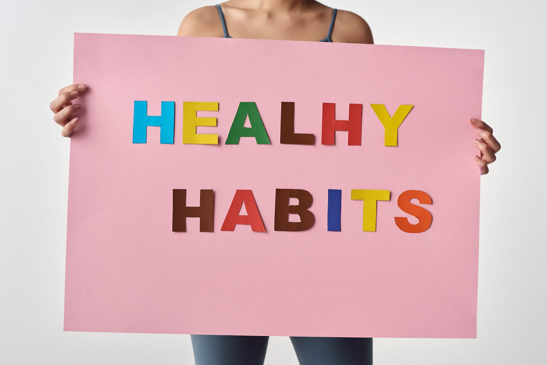 person holding a pink poster with message: Healthy Habits
