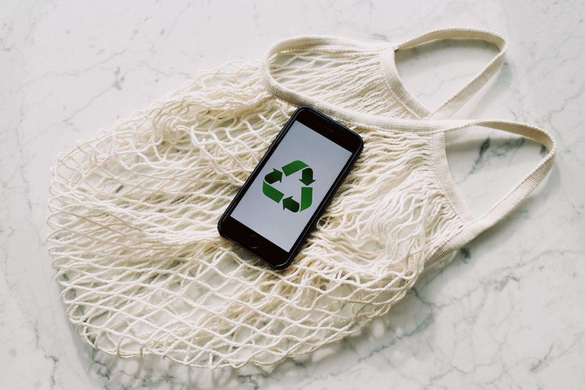 mobile phone with green recycling sign and mesh bag (NGOs with sustainablle development)