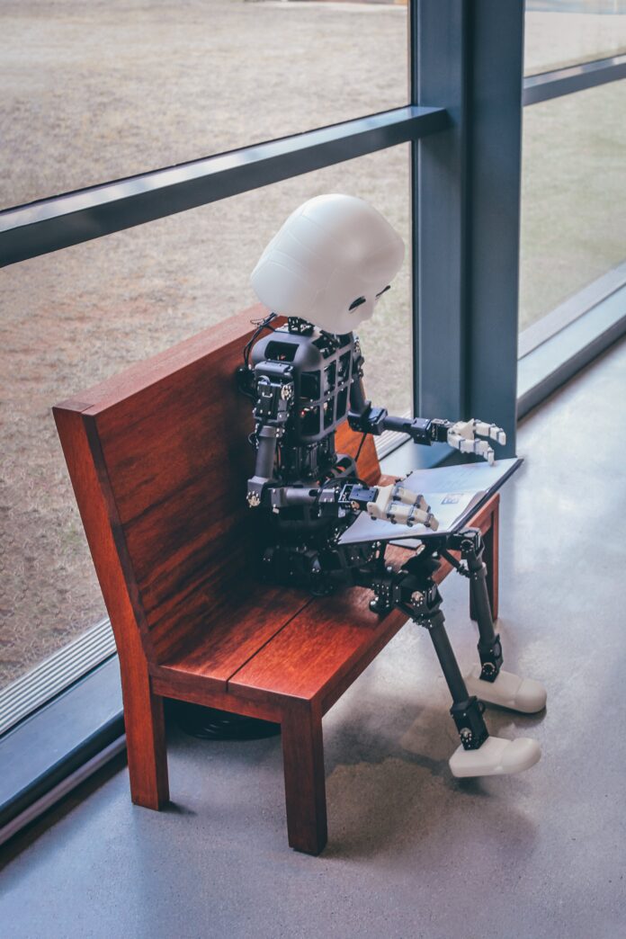 pexels-andrea-de-santis-17325393 Robot holding laptop to "represent" how the future of work could be