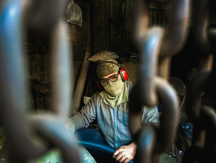 pexels-photo-33547503 industrial worker through chains unique perspective