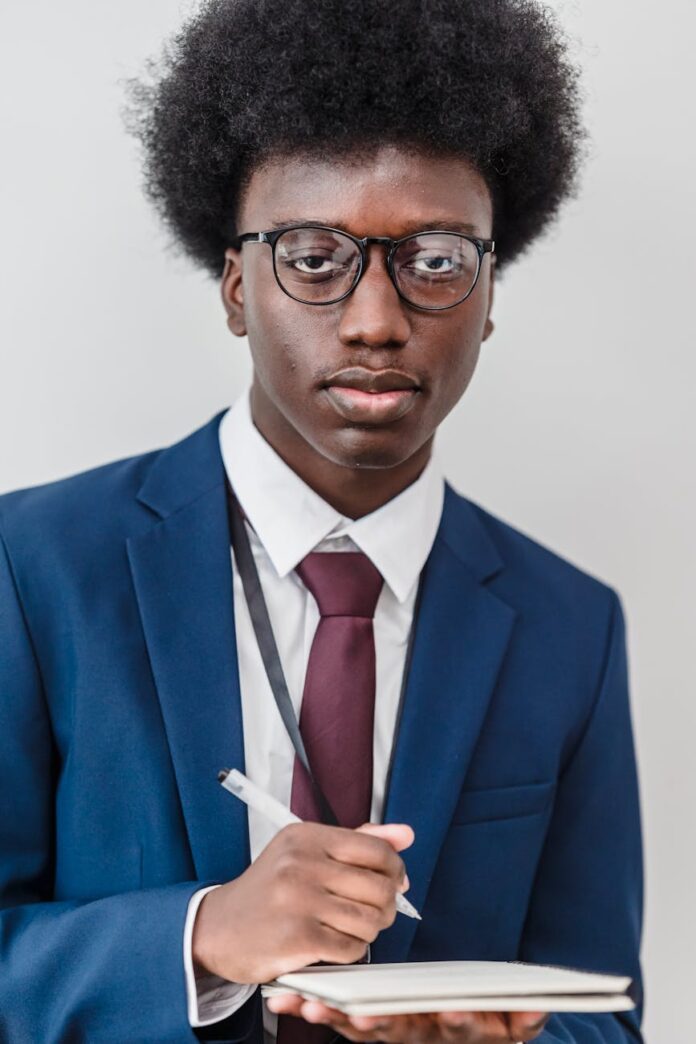 a man in eyeglasses and a suit writing on a notepad